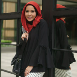 Wanita asia dengan warna hijab merah dan baju hitam menggunakan celana garis-garis hitam