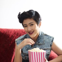 Wanita asia dengan gaya rambut long pixie cuts sedang menyantap popcorn.