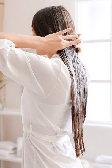 wanita dengan rambut panjang sedang menggunakan conditioner pada rambut