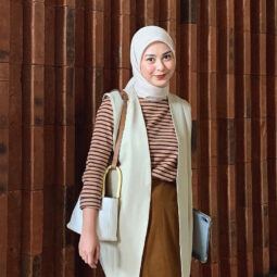 Selebgram hijab Dianty berdiri mengenakan baju motif stripes dan rok panjang warna cokelat dengan blazer dan hijab warna krem.