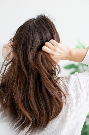 wanita dengan rambut panjang berwarna cokelat sedang menyentuh rambut karena kepala gatal akibat kutu rambut