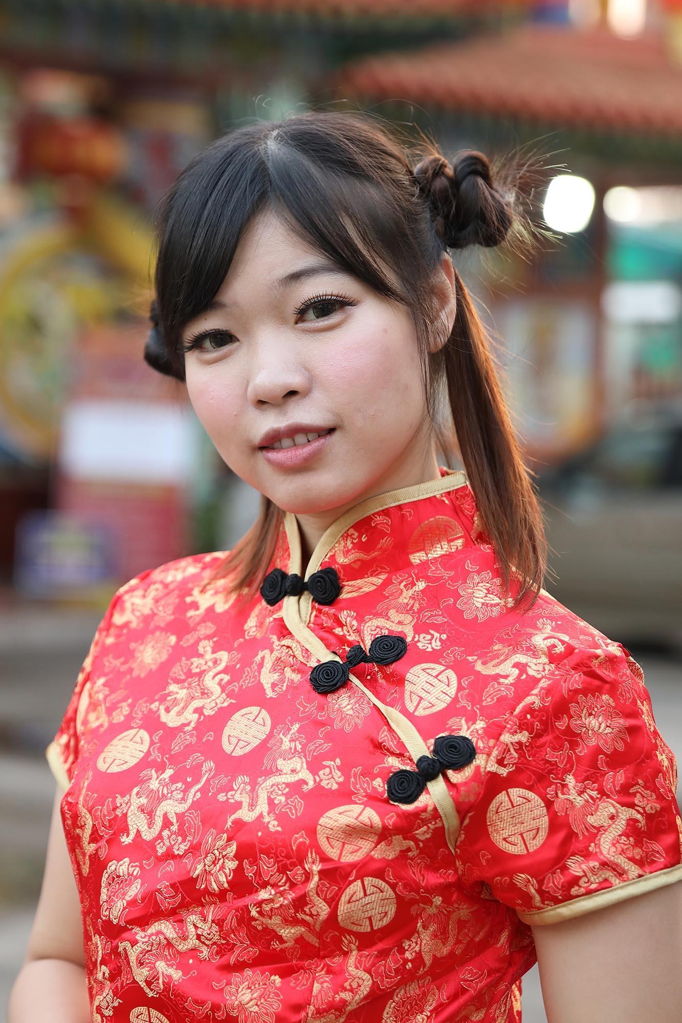 wanita asia dengan rambut dicepol dua dan mengenakan baju khas imlek