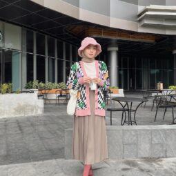 Wanita Indonesia memakai hijab dan bucket hat dengan outfit bergaya preppy.