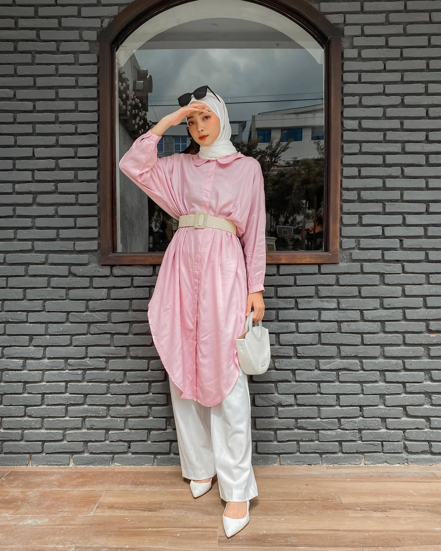 Wanita Indonesia mengenakan kemeja oversized warna pink dan hijab warna putih
