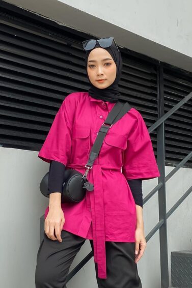 Wanita Indonesia mengenakan padanan baju pink fuchsia dengan hijab warna hitam.