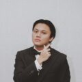 Penyanyi pria Indonesia Rizky Febian mengenakan setelan jas warna hitam dengan gaya rambut belah tengah klimis
