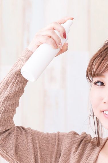 Wanita asia menggunakan dry shampoo pada poni