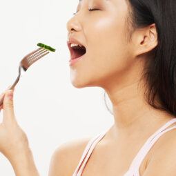 wanita asia dengan rambut panjang sedang menyantap sayuran sebagai diet
