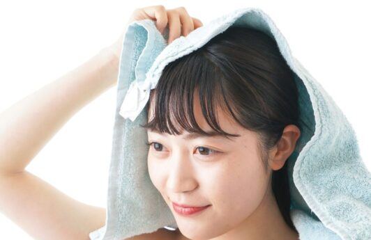 Wanita Asia sedang mengeringkan rambut menggunakan handuk