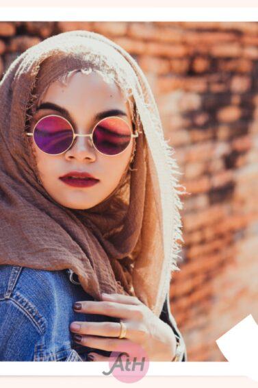 Wanita Asia mengenakan hijab pashmina crinkle warna cokelat dan kacamata hitam bulat.