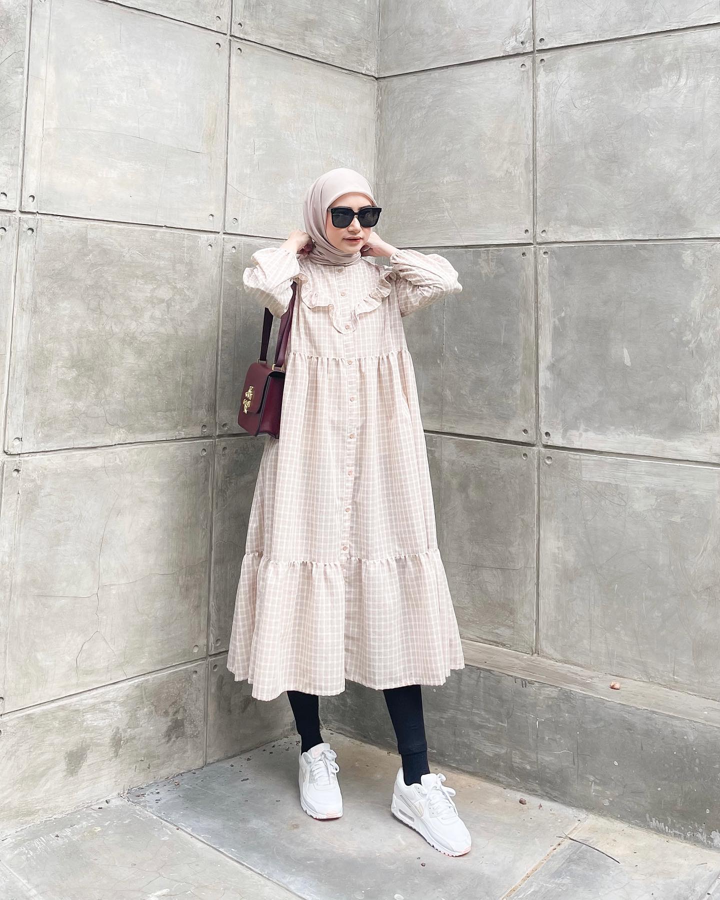 Selebgram hijab dan model Bahjatina memakai midi dress motif kotak-kotak warna krem dan celana legging.