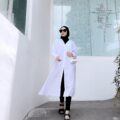 Wanita Indonesia berdiri mengenakan baju tunik putih dan legging hitam.