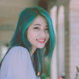 Wanita Asia dengan warna rambut hijau tosca sedang tersenyum