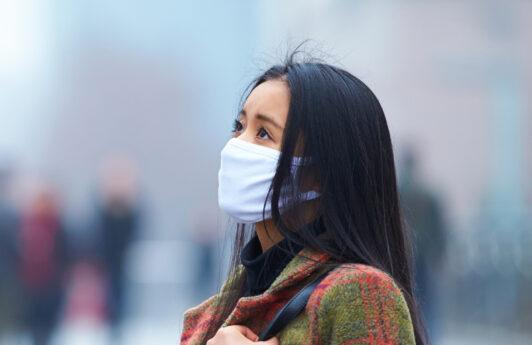 wanita asia sedang memakai masker karena polusi udara
