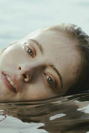 mujer caucásica sumergida en el agua con la cabeza fuera, mascarilla para el pelo