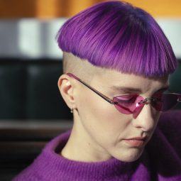 mujer de perfil con corte taza en pelo color violeta sobre rapado