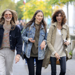 Tres mujeres caminando por la calle, solo a una se le ve el rostro entero, lleva el pelo suelto, lacio con raya al medio