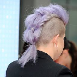 Vista de atrás de mujer de cabello lila, rapado a los costados con una cresta peinada tipo bubbly 