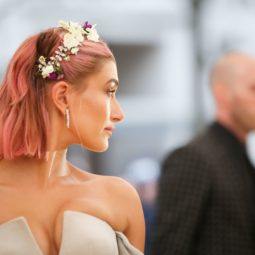 Mujer vestida de novia, lleva melena carre color rosa, peinada hacia atrás con una corona de flores a modo de vincha