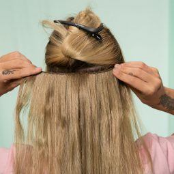 mujer rubia aplicando extensiones de pelo