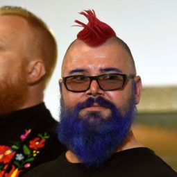 Dos hombres de barba y cabello rapado a los costados con cresta; uno es rubio, el otro lleva el cabello rojo y la barba azul 