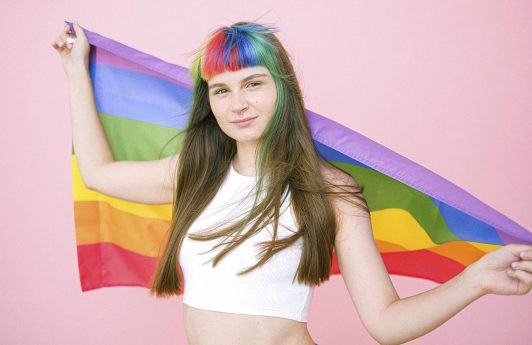 mujer de pelo largo con flequillo recto y pelo arcoiris con bandera del orgullo