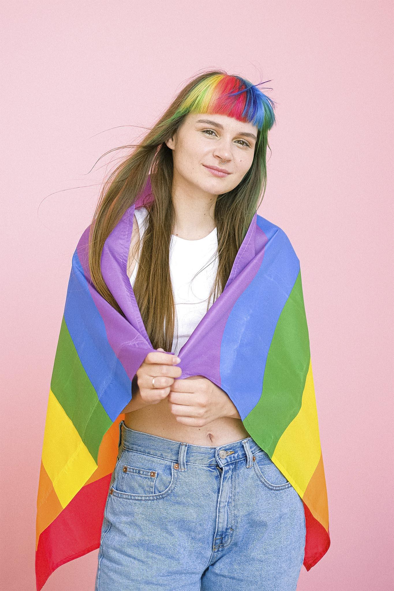 mujer de pelo largo con flequillo recto y pelo arcoiris con bandera del orgullo