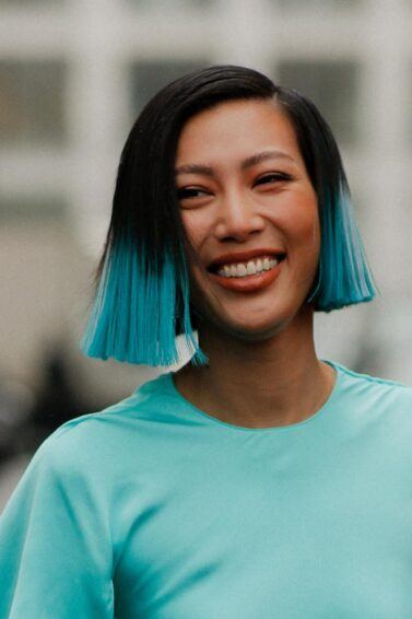 mujer asiatica de pelo corto tipo bob lacio negro con puntas de color turquesa, pelo turquesa