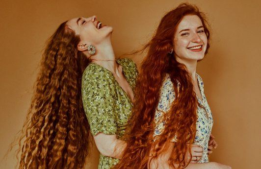 mujeres de pelo largo con ondas sonriendo, como hacer crecer el pelo rápido