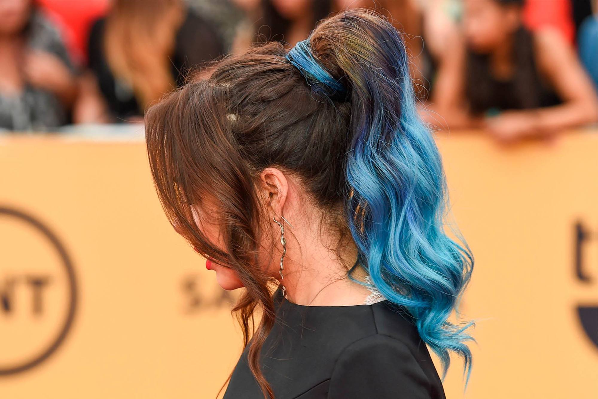 mujer de perfil con cola de caballo alta con ondas y puntas de pelo azul
