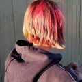 mujer de espaldas con mechas rojas en pelo rubio y corte en capas
