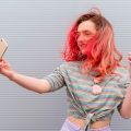 mujer de perfil tomando una selfie con pelo teñido y mechas rojas