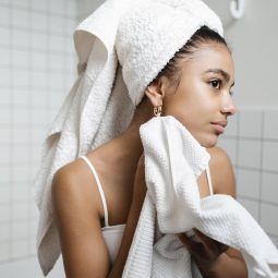 mujer con toalla en la cabeza frente al espejo, shampoo sin sal