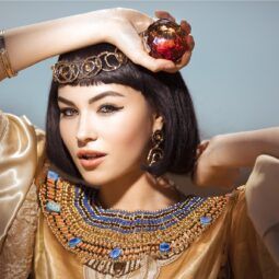 mujer de pelo corto negro con flequillo y tiara dorada, peinados egipcios