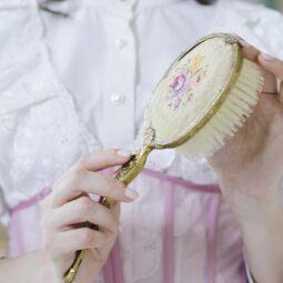 detalle de manos de mujer sosteniendo un cepillo antiguo, tipos de cepillos para el cabello