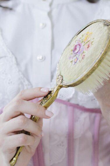 detalle de manos de mujer sosteniendo un cepillo antiguo, tipos de cepillos para el cabello