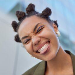 mujer sonriente con bantu knots, peinados con rulos para pelo corto