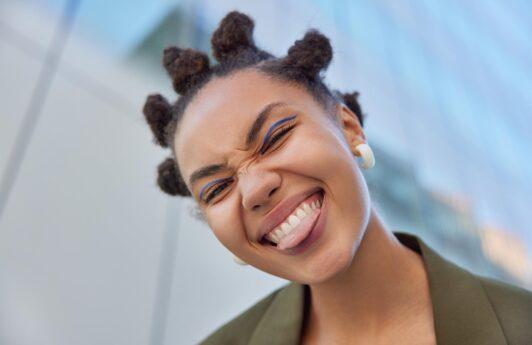 mujer sonriente con bantu knots, peinados con rulos para pelo corto