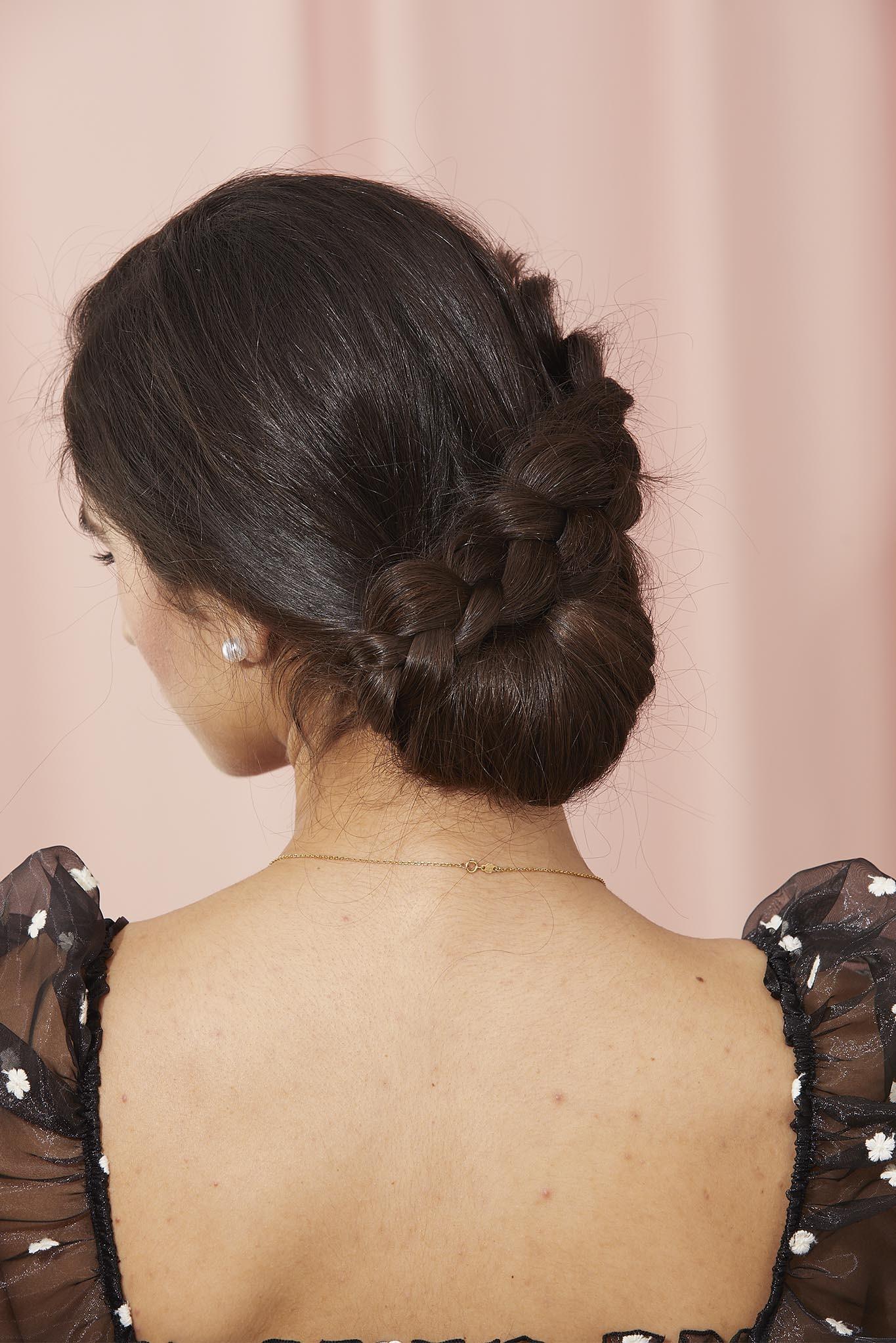 mujer de espaldas de pelo negro lacio con recogido bajo y trenza en línea oblicua, recogido peinados con trenzas