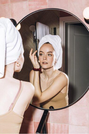 mujer frente al espejo aplicando acido glicolico en la cara