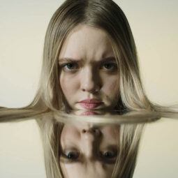 mujer de pelo largo rubio lacio y su reflejo sobre espejo, botox capilar