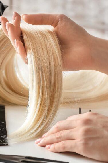 detalle de mano de mujer sosteniendo extensiones de pelo rubias