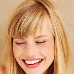 Best hair treatment for damaged hair: Close up of woman with straight blonde hair and a fringe.