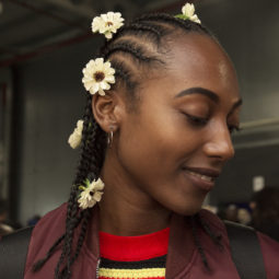 Cornrows: Woman at AfroPunk with hair in cornrow braids with sunflowers placed throughout her hair.