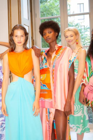 Shampoo: Five models backstage at Pucci SS19 show with different hair types and textures, from straight brown to short afro hair. All Models wearing bold coloured outfits.