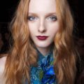 Red hair: Model with long wavy ginger balayage hair wearing a blue top.