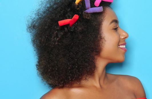 Black woman with curling rods in her afro hair