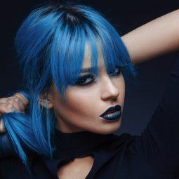 woman with straight sleek bright blue hair fringe dark roots