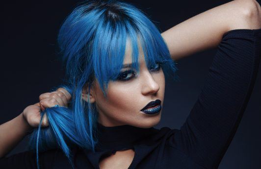 woman with straight sleek bright blue hair fringe dark roots