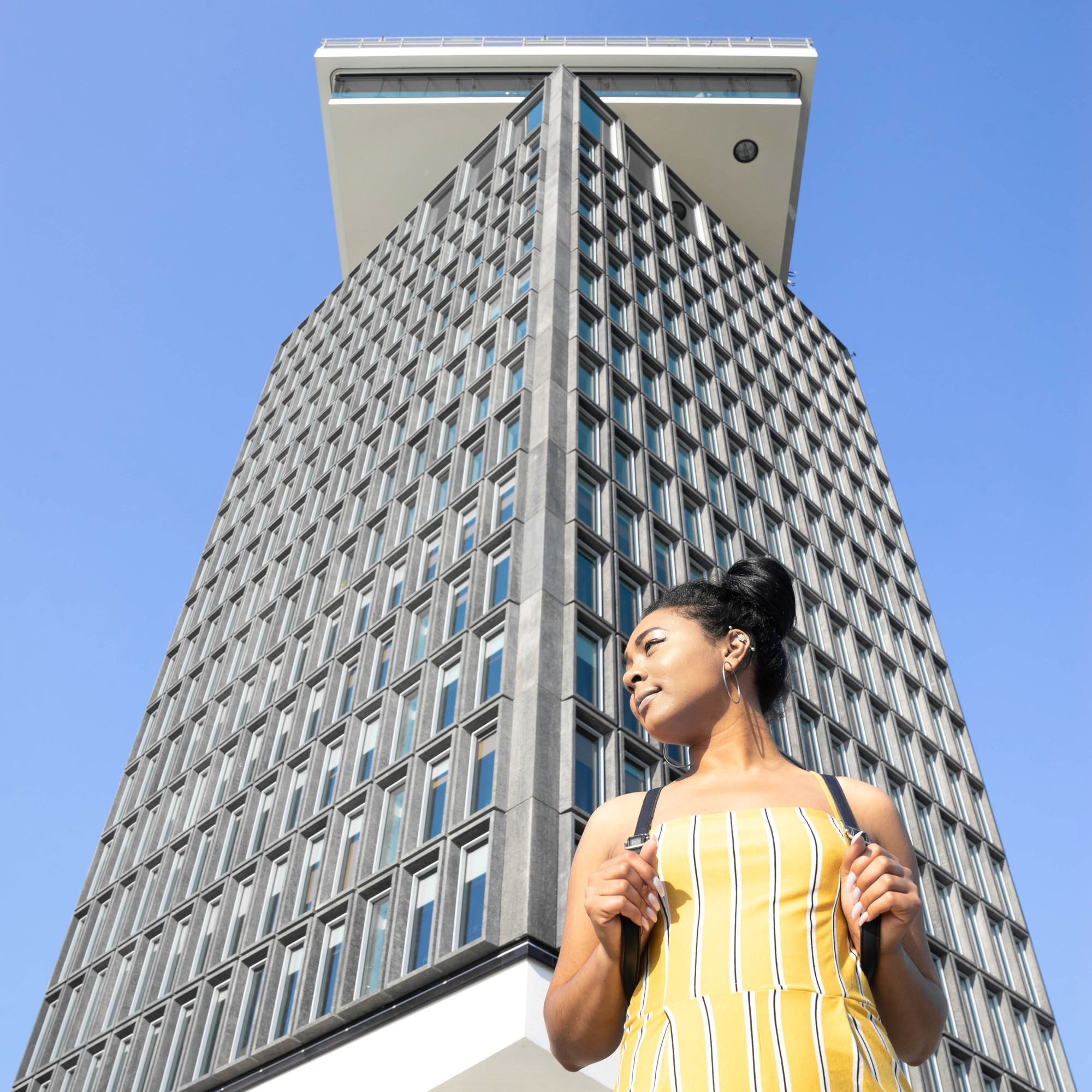 woman with a topknot hairstyle standing in front of a building